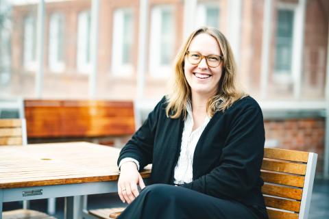 Amy Johnson sits in a greenhouse and smiles for a portrait.